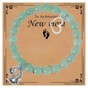 Macro shot of light green beaded bracelet with baby footprint charm on a gift card