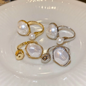 Detail view of gold and silver irregular pearl rings arranged on a white ceramic plate