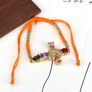 Detailed close-up of orange braided rope bracelet with colorful zircon gold cross charm