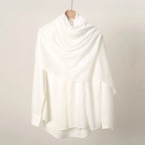 Detail of soft white cotton linen scarf texture draped over a matching white shirt