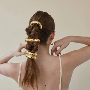 Detail of 18k gold plated curved hair clip and matching hoop earrings on model