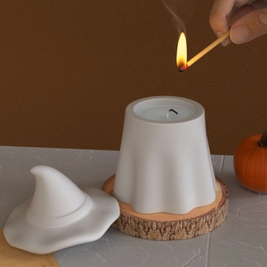 Ghost candle jar with wizard hat lid on wood base being lit with a matchstick