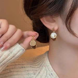Detail of elegant gold double circle earrings with marble inlay worn by a model