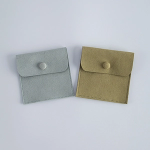 Close-up of light gray and olive green velvet jewelry pouches with snap button closures