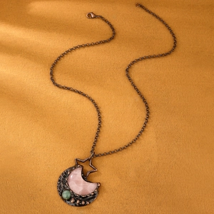 Detailed view of bohemian bronze star and moon pendant with rose quartz and green stone