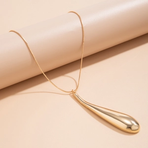 Macro shot of long gold water drop earrings with a sleek minimalist geometric pendant