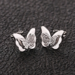 Macro shot of silver 3D butterfly stud earrings featuring layered textured wings on leather