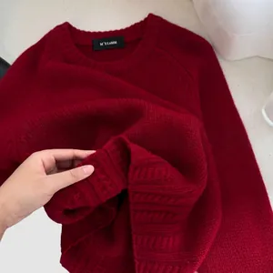 Women's oversized red cable knit sweater with ribbed texture and thick crew neck design