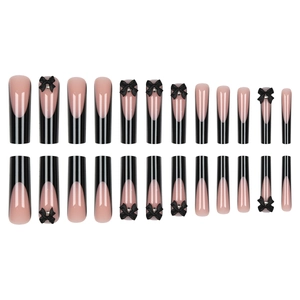 Faux ongles French longs noirs avec nœuds 3D et strass sur fond blanc immaculé