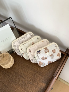 Close-up of quilted card holders in floral, dot, and bear patterns on a wood surface