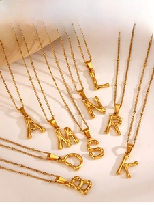 Vue détaillée de divers pendentifs alphabet dorés avec de fines chaînes à billes chic