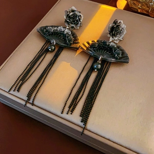 Detail of fan-shaped tassel earrings with floral accents and dark metallic finish