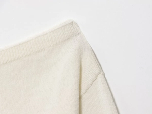 Close-up of soft cream knit fabric texture with minimalist weave for off-shoulder sweater