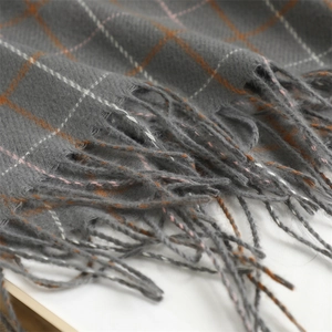 Close-up of gray plaid scarf texture with soft tassels and woven fringe details