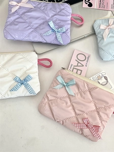 Quilted cosmetic bags with bow knots in purple white pink and blue colors on a desk