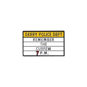 Macro shot of Derry Police Dept enamel pin with Remember the Curfew warning text