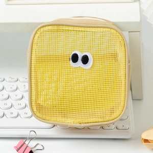 Detailed close-up of yellow mesh storage bag with embroidered big eyes on a desk