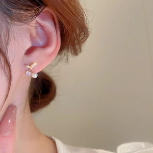 Nahaufnahme von Kirsch-Ohrsteckern mit Perle und Zirkonia am Ohr eines weiblichen Models