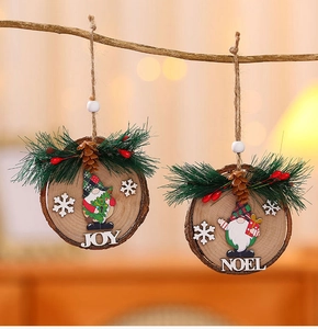 Close-up of wooden Christmas gnome ornaments with JOY and NOEL letters on pine branches