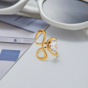 Macro detail of gold-plated wavy ring featuring a large oval-cut clear zircon stone