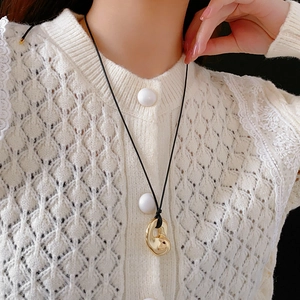 Detail of adjustable gold irregular loop pendant necklace on black cord with model