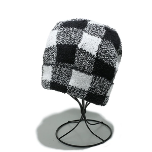 Close-up of black and white checkerboard knit beanie showing thick plush fabric texture