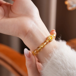 Vue détaillée d'un bracelet en perles de citrine jaune avec un pendentif hulu doré