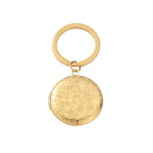 Close-up of golden circular locket keychain with intricate floral engraving and mirror finish