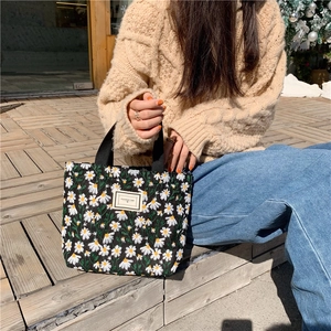 Gros plan détaillé des broderies marguerites sur le sac en toile noire avec poignées