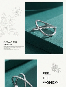 Detailed view of silver cross ring with pavé-set crystals on elegant green surface