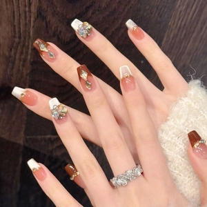 Détail macro de faux ongles longs cercueil avec finition œil de chat brun et strass