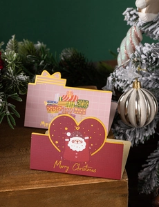 Close-up of 3D folding Christmas gift cards with gold foil lettering on wooden surface