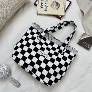 Close-up of black and white checkered canvas tote with lace trim and lifestyle props