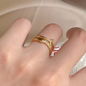 Close-up of double-layered gold ring with twisted texture and small white gemstones