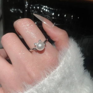 Detailed view of an elegant silver pearl ring with sparkling cat ears on a finger