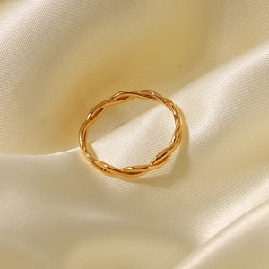 Detailed view of an 18K gold-plated twisted rope ring on elegant beige silk fabric