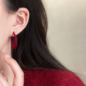 Close-up of model wearing large dark red flocked hoop earrings for autumn fashion