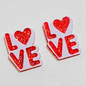 Détail de boucles d'oreilles cœur pailleté rose avec texte LOVE pour la Saint-Valentin