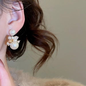 Gros plan d'un mannequin portant des boucles d'oreilles en or 14k avec perles et zircons