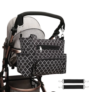 Detail of multi-pocket diaper bag with clover pattern hanging on a stroller handle