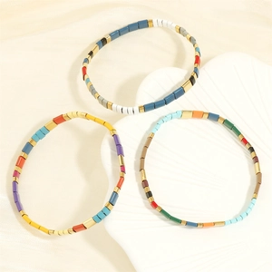 Detail of colorful Tila bead stretch bracelets featuring vibrant enamel blocks and gold spacers