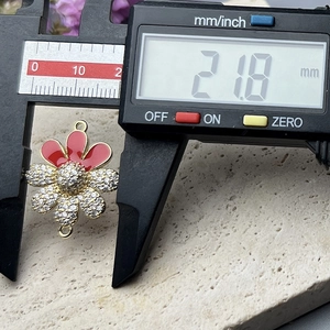 Macro detail showing 21.8mm width measurement of a zircon flower pendant with a caliper