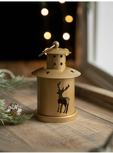 Detail of golden metal Christmas lantern with reindeer cutout on a wooden tray