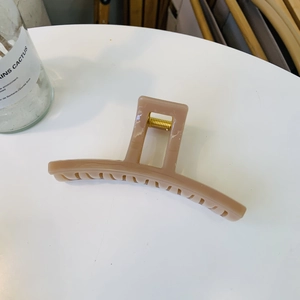 Detail of a caramel translucent claw clip showing the durable gold metal spring mechanism