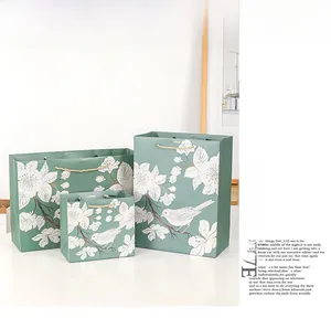 Three sizes of Morandi green gift bags with floral and bird patterns and gold handles