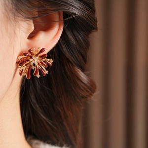 Gros plan de boucles d'oreilles fleurs en émail bordeaux et zircon sur un mannequin