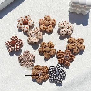 Flat lay of plaid and polka dot fabric flower charms for DIY crafts and hair accessories