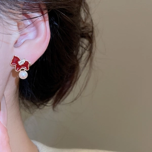 Detail of red enamel bear earrings with gold trim and a hanging pearl on a female model