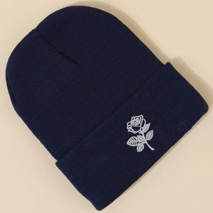 Close-up of navy blue knit beanie featuring delicate white rose embroidery detail