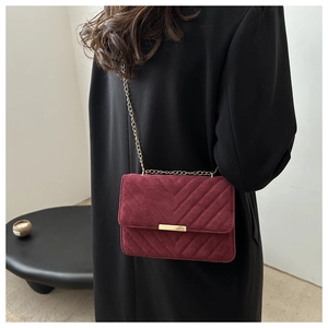 Detail view of burgundy faux suede crossbody bag with V-shaped quilting and chain strap